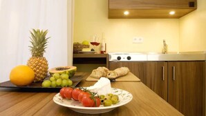 A kitchen with wooden cabinets, a countertop with fruits, a cutting board, and a stove. - GuestHouse Heidelberg (Heidelberg)