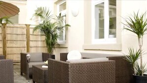 A patio area with wicker furniture, a bamboo fence, and potted plants. - GuestHouse Heidelberg (Heidelberg)