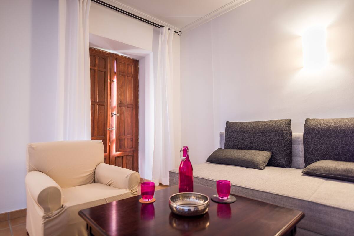 A living room with a sofa, a coffee table, and a door leading to another room.