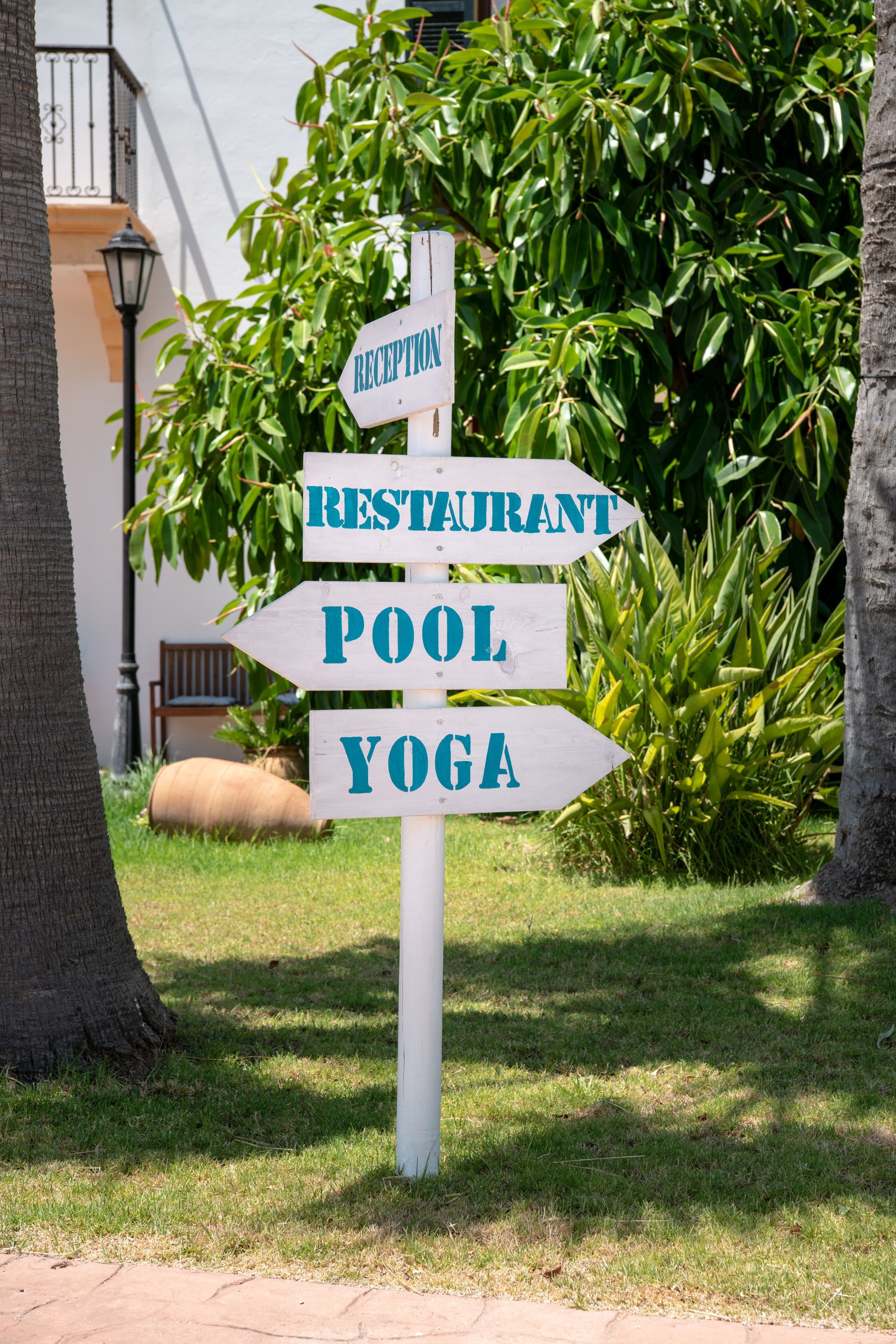 A directional signpost with arrows pointing to 'RECEPTION,' 'RESTAURANT,' 'POOL,' and 'YOGA.'