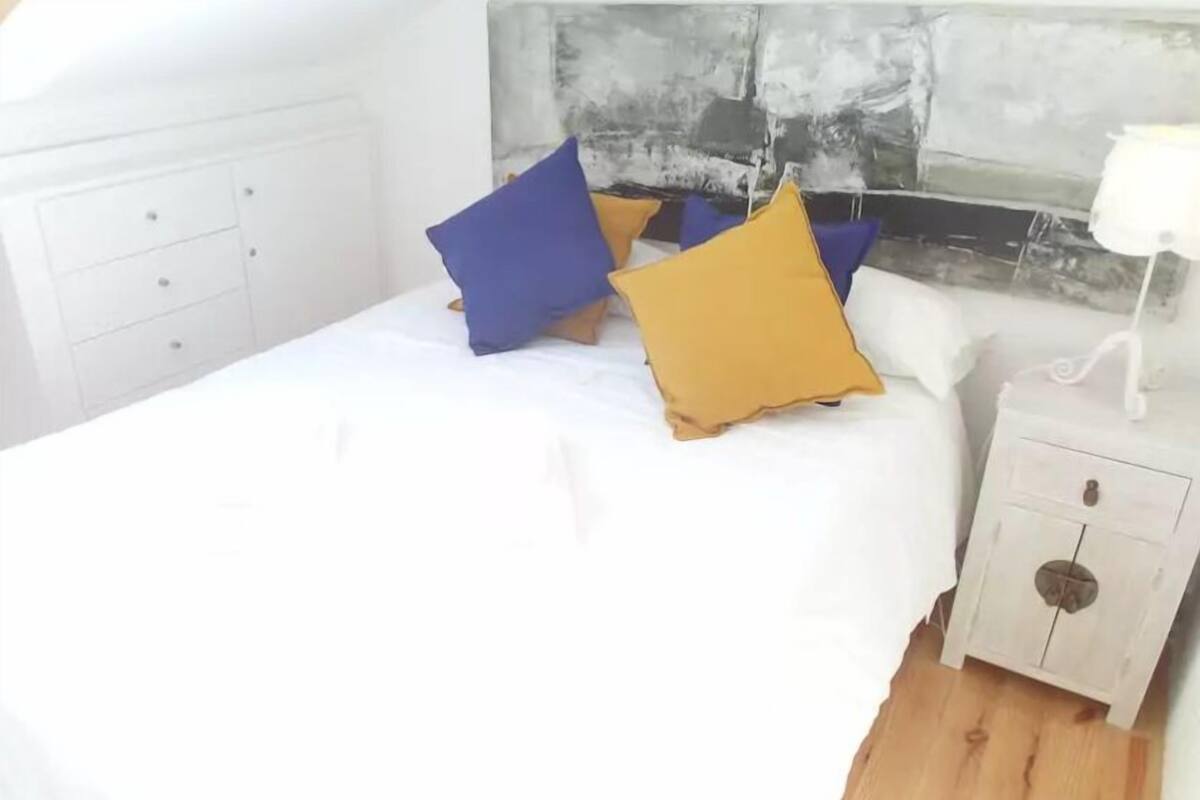 Une chambre à coucher avec un lit, des tables de chevet blanches et un tableau mural.