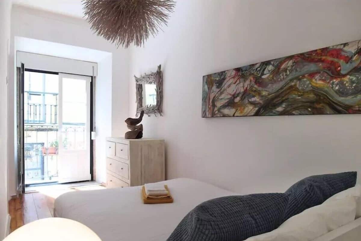 Une chambre à coucher avec un lit, une commode, un miroir et un tableau.