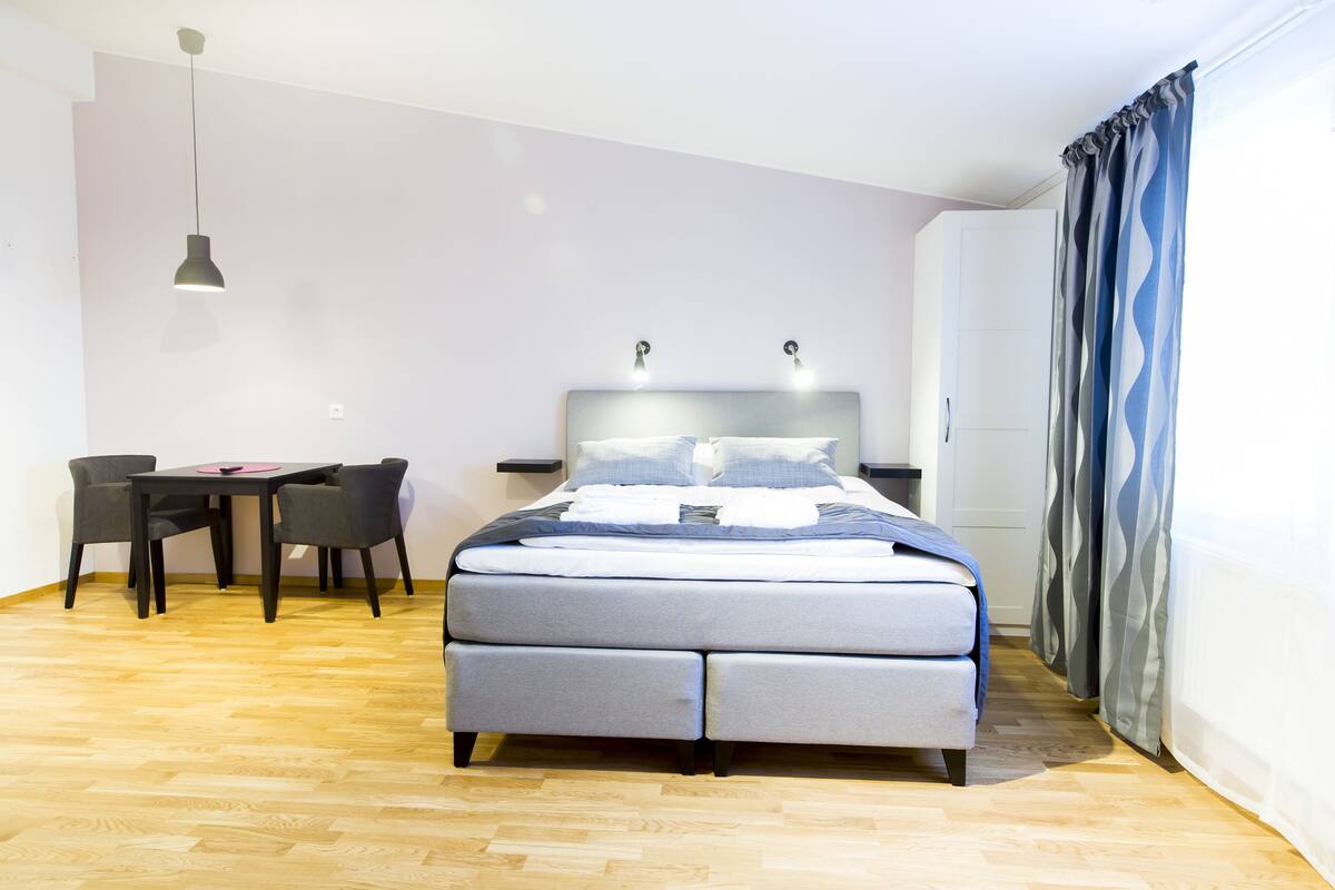 A modern bedroom with a bed, bedside tables, a desk, and chairs.