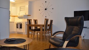 A compact living space with a dining area, a modern kitchen, and a seating area with a leather chair. - Simloc Hotel Drottninggatan (Arjeplog)