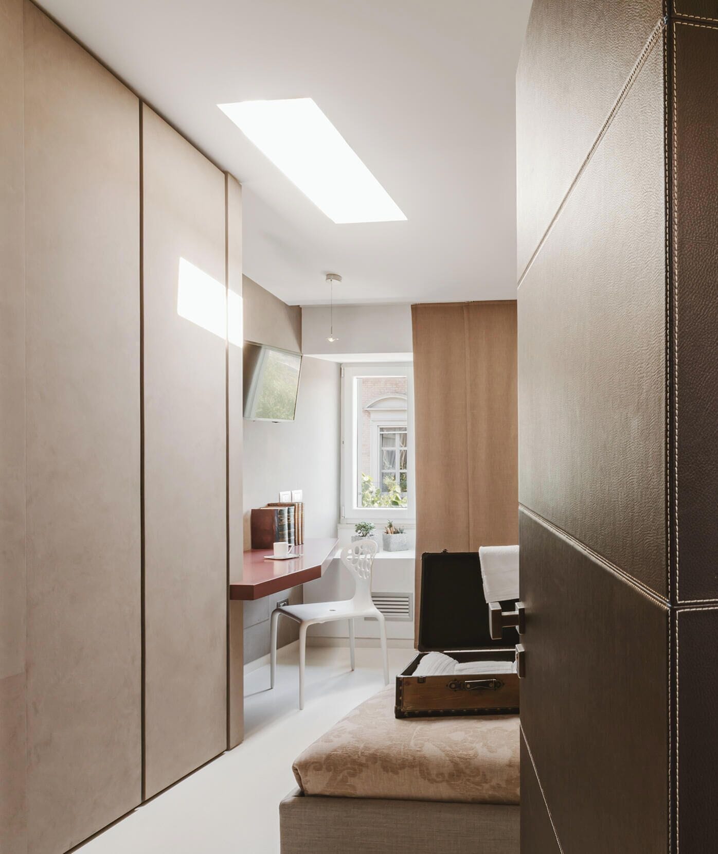 A modern bedroom with a bed, bedside table, and a desk with a chair.