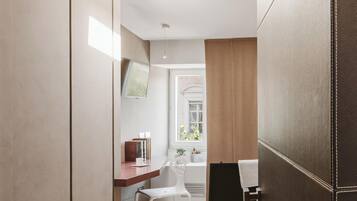 A modern bedroom with a bed, bedside table, and a desk with a chair.