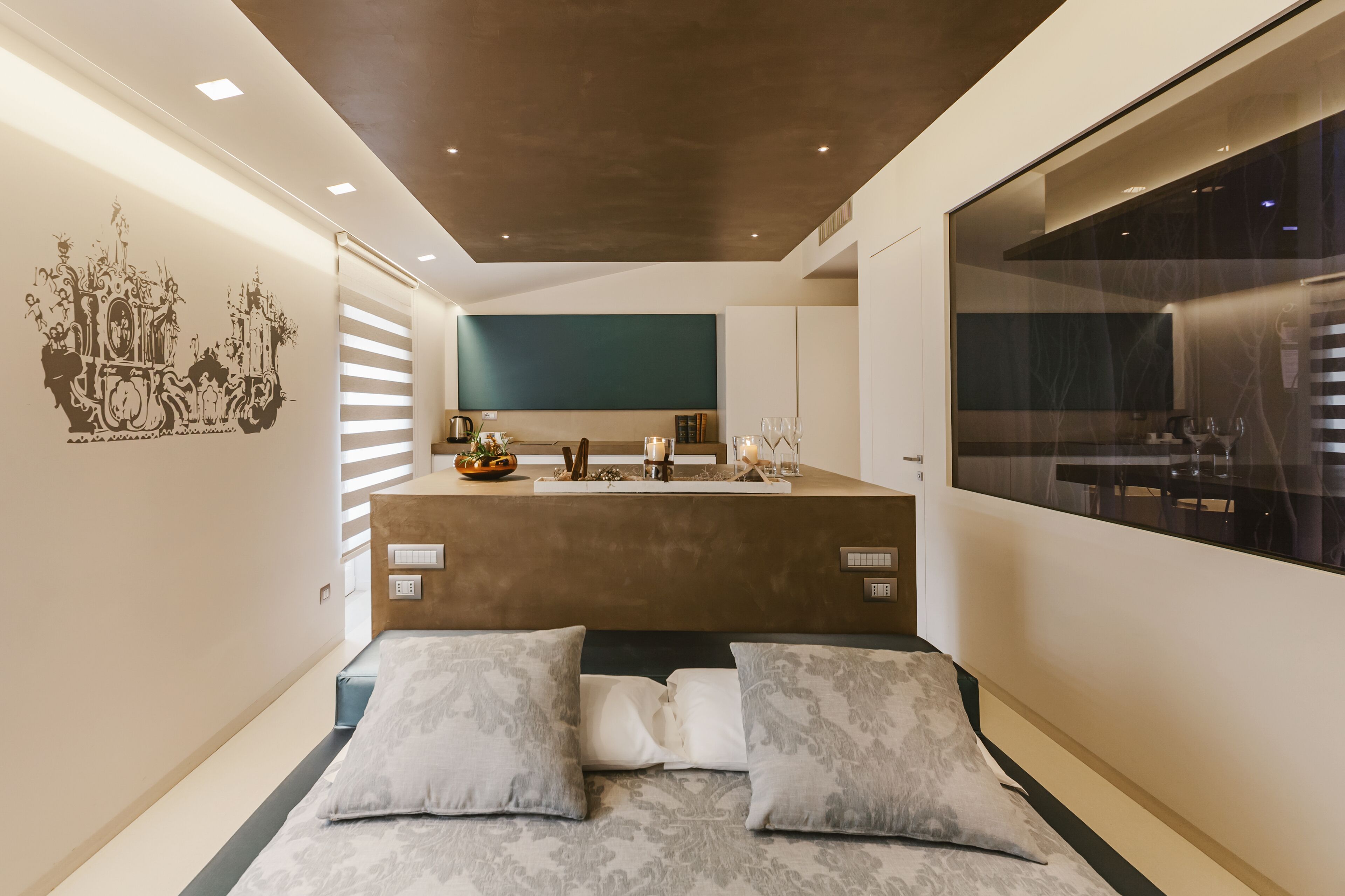 Ein modernes Hotelzimmer mit einer zentralen Insellösung, einem großen Fenster und einem dekorativen Wandbild.