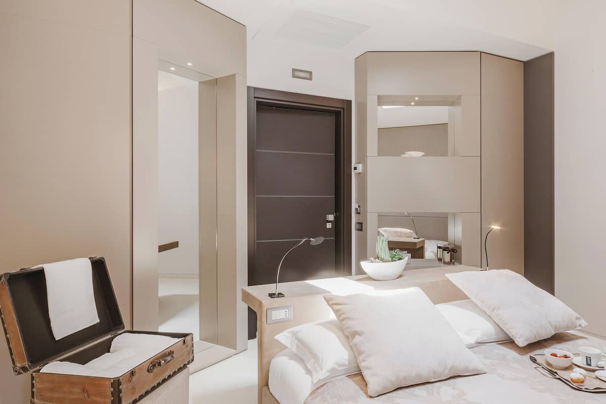 Una habitación de hotel moderna con cama, mesita de noche y maleta.