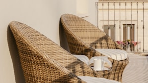 Two wicker lounge chairs with cushions, positioned against a wall on a tiled patio area. - Residenza del Monaco Bianco (Matera)
