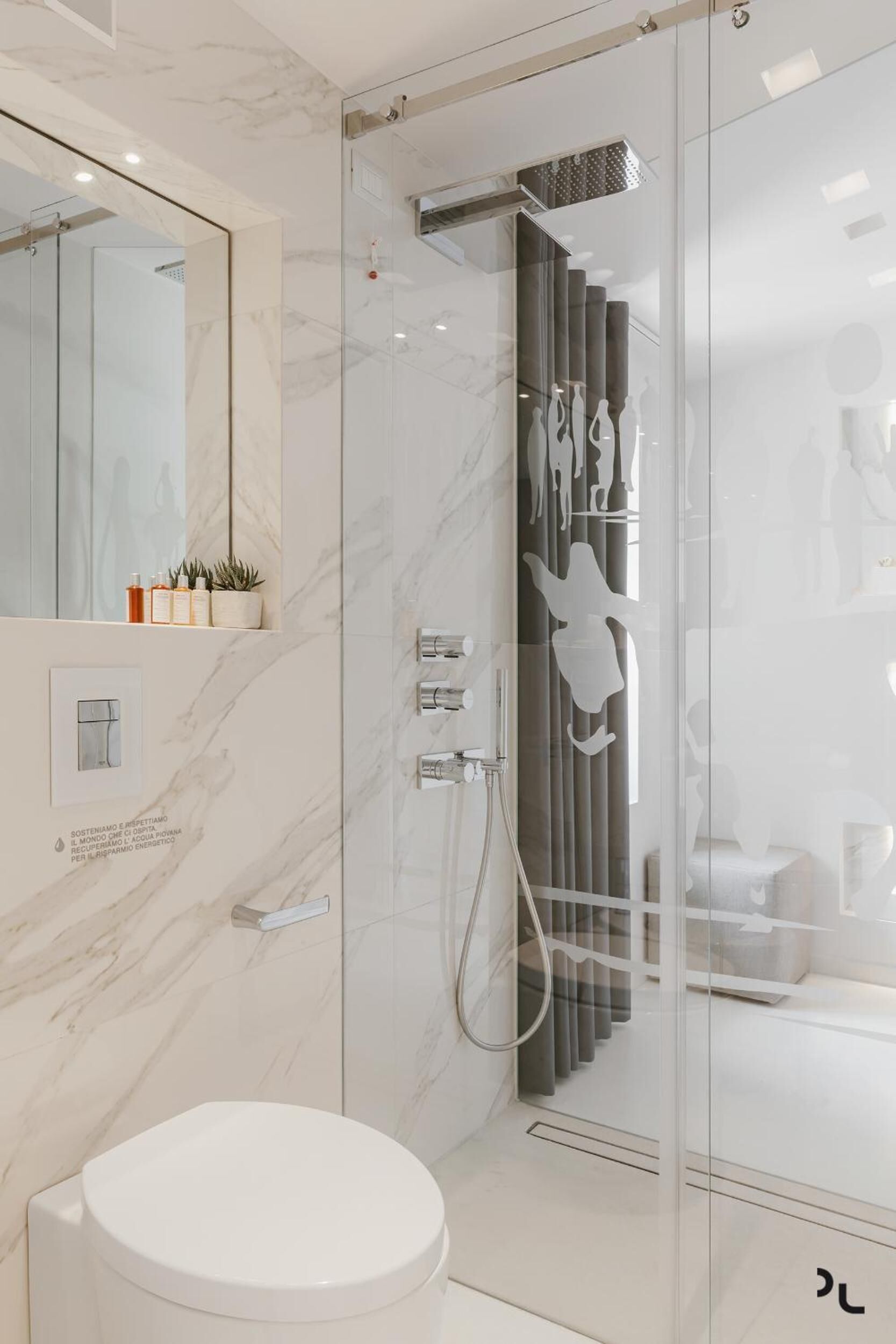A modern bathroom with a glass shower enclosure, a white toilet, and a marble wall.