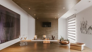 A modern interior with a wooden table, candles, and a flat-screen TV on the wall. - Residenza del Monaco Bianco (Matera)