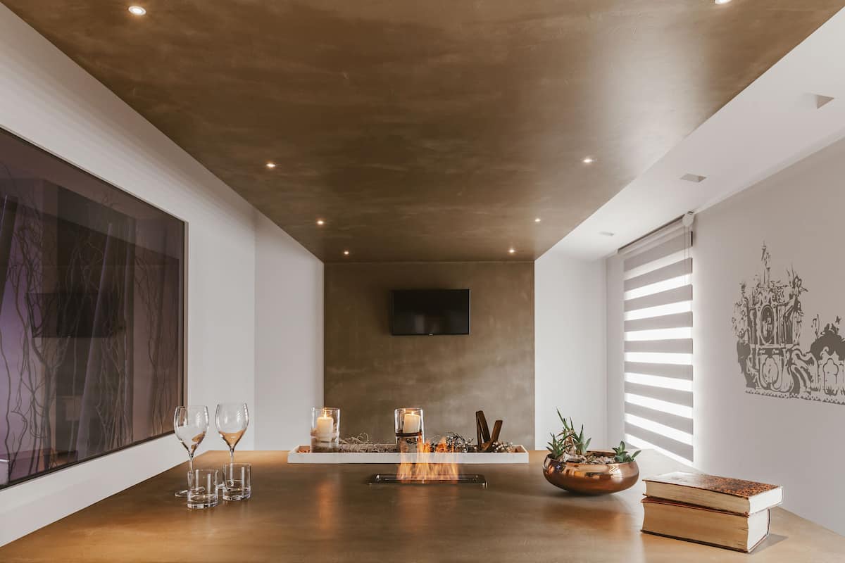 Un interior moderno con una mesa de madera, velas y un televisor de pantalla plana en la pared.