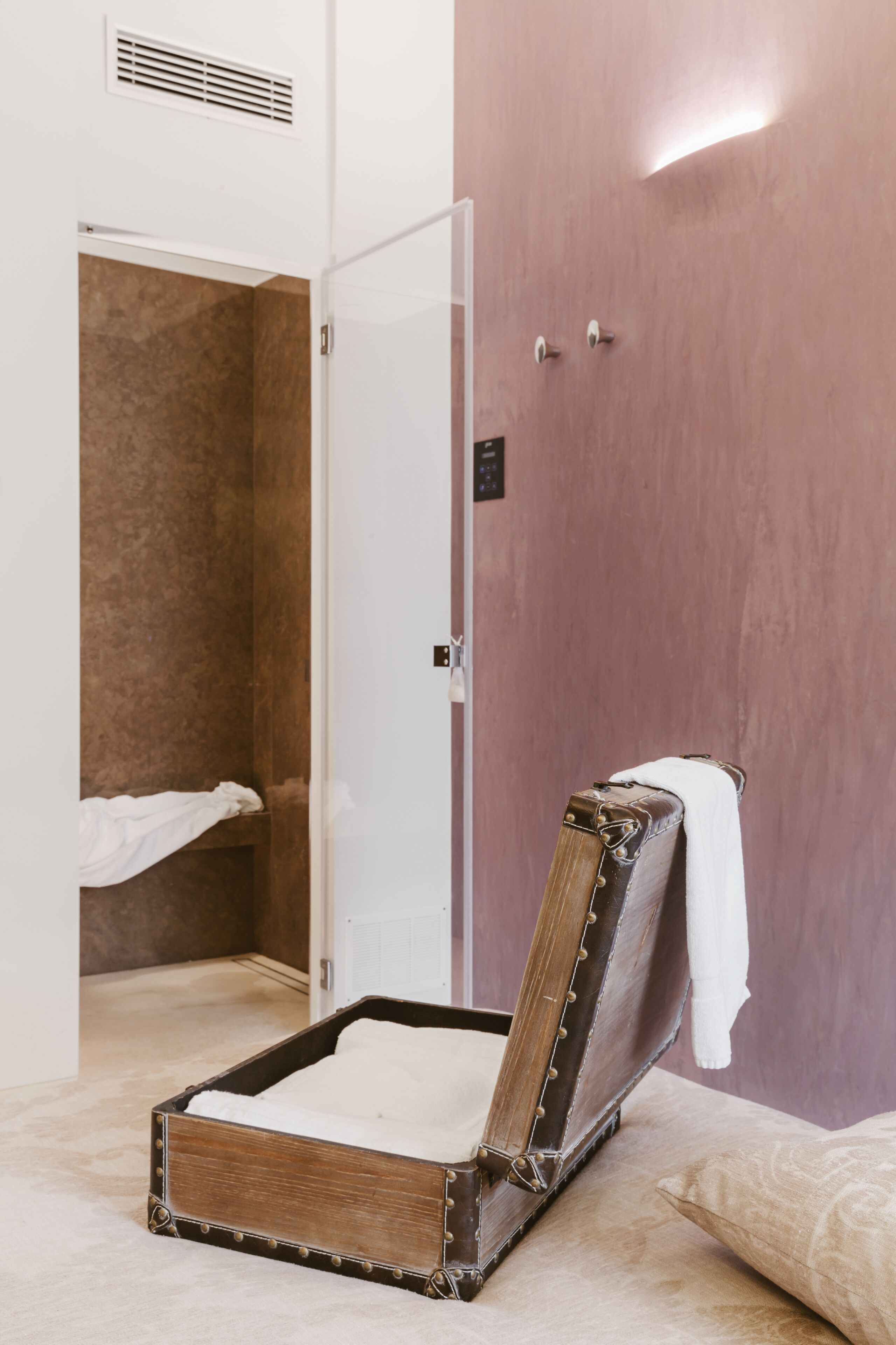 Quarto com uma cama, área de chuveiro e uma porta com uma toalha pendurada.