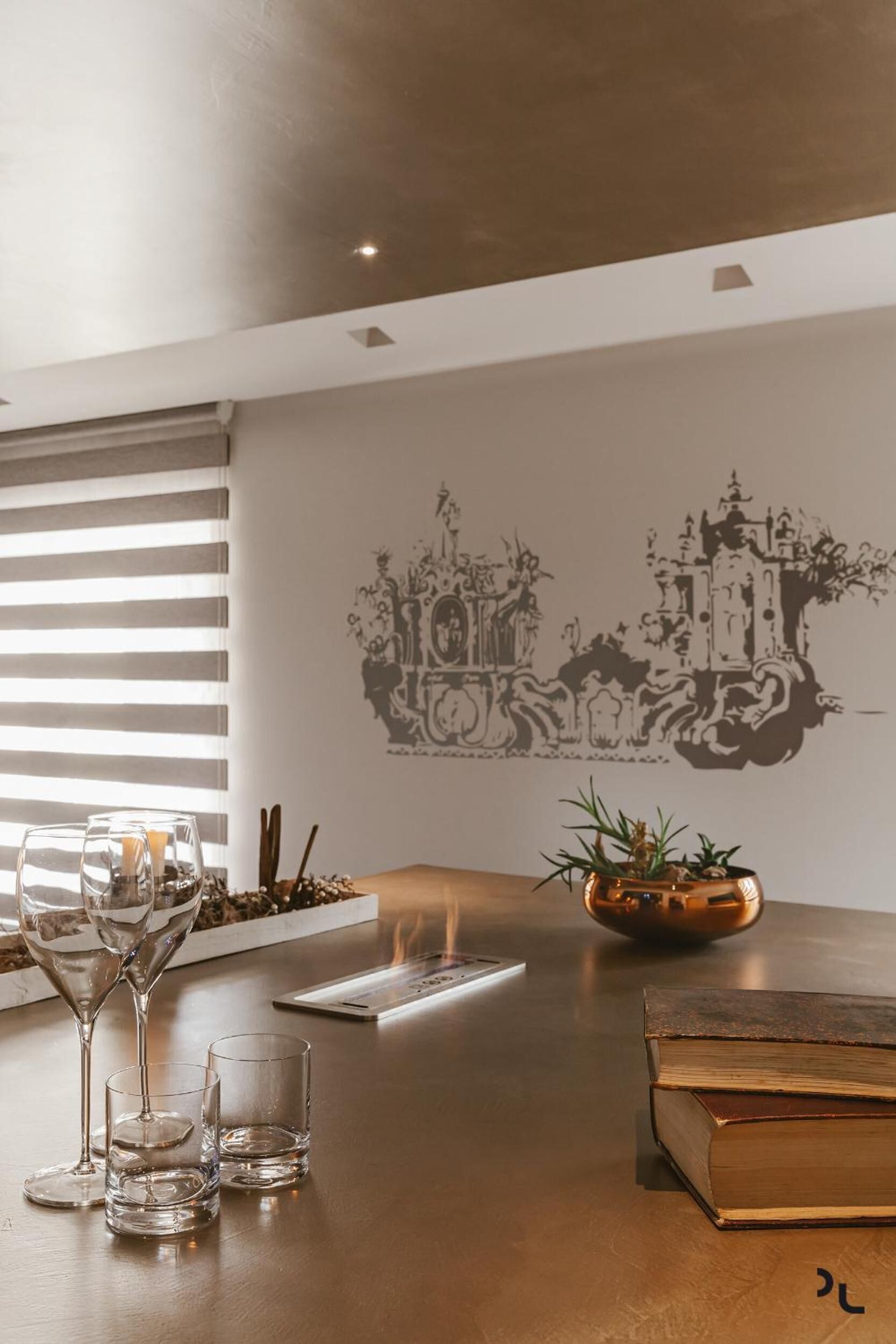 Un espace de salle à manger moderne avec une table en bois, des verres à vin, une bougie et un élément décoratif mural.