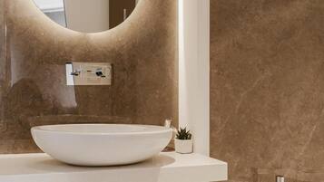 Une salle de bain moderne avec un miroir rond, un lavabo blanc et une baignoire.