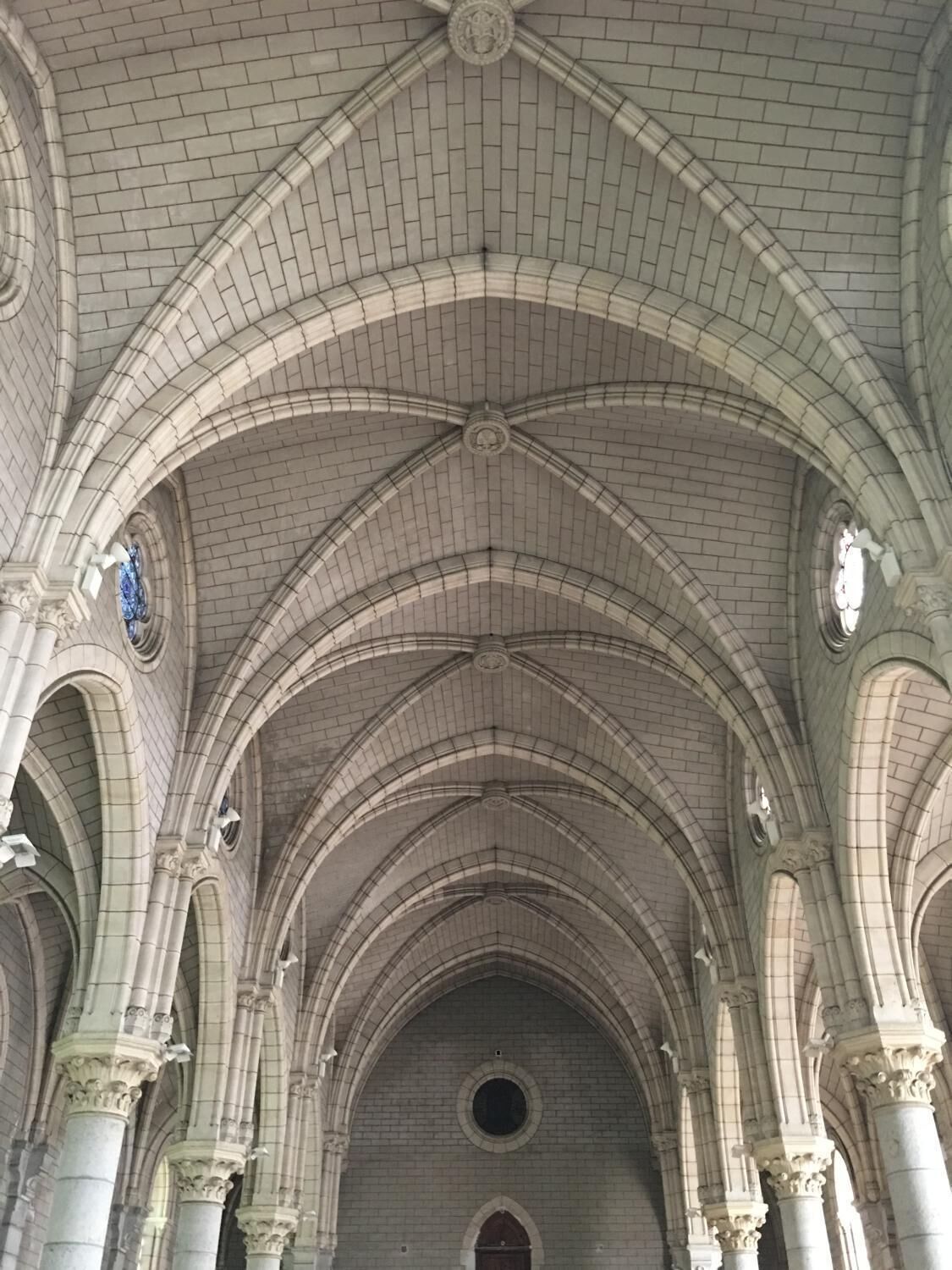 A cathedral interior with high vaulted ceilings, arched windows, and columns.