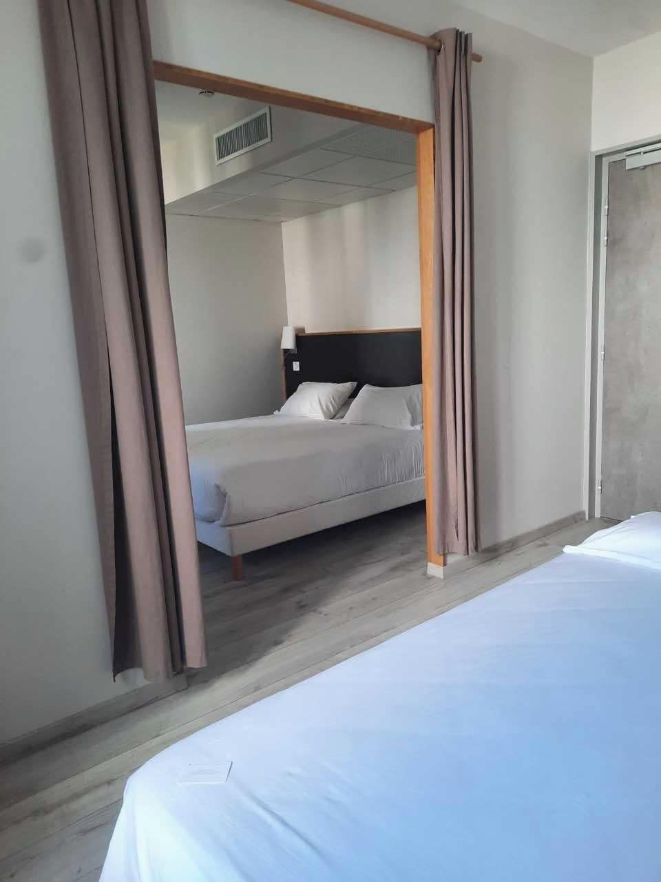 A hotel room with a bed, a window, and a curtain.