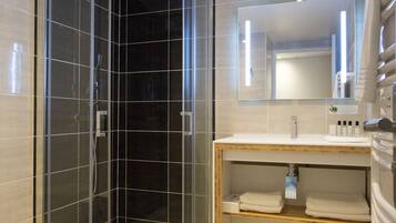 A modern bathroom with a glass-enclosed shower, a wooden vanity, and a large mirror above the sink.