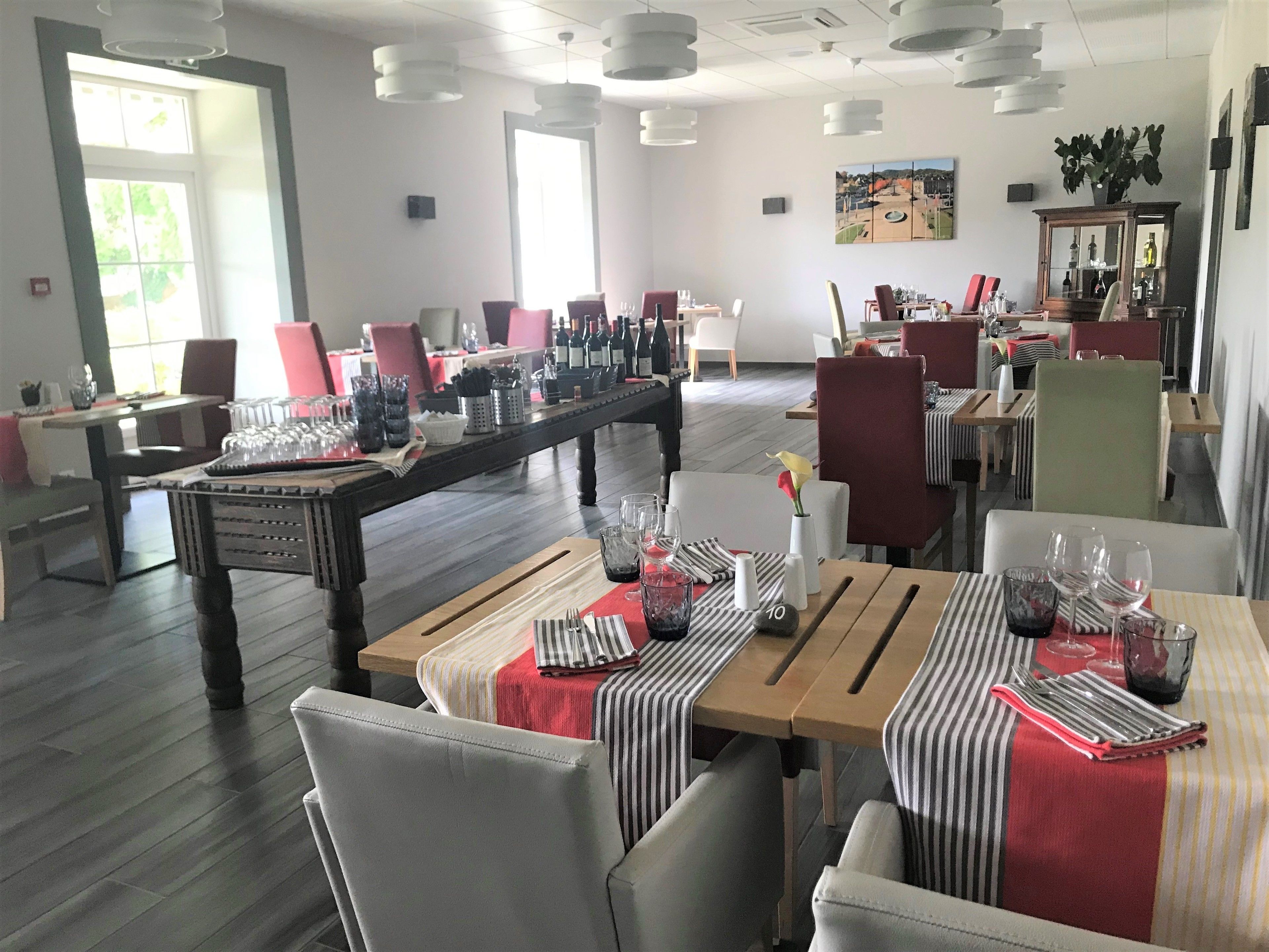 Comedor con mesas dispuestas para una comida, un ventanal y vistas a la ciudad.