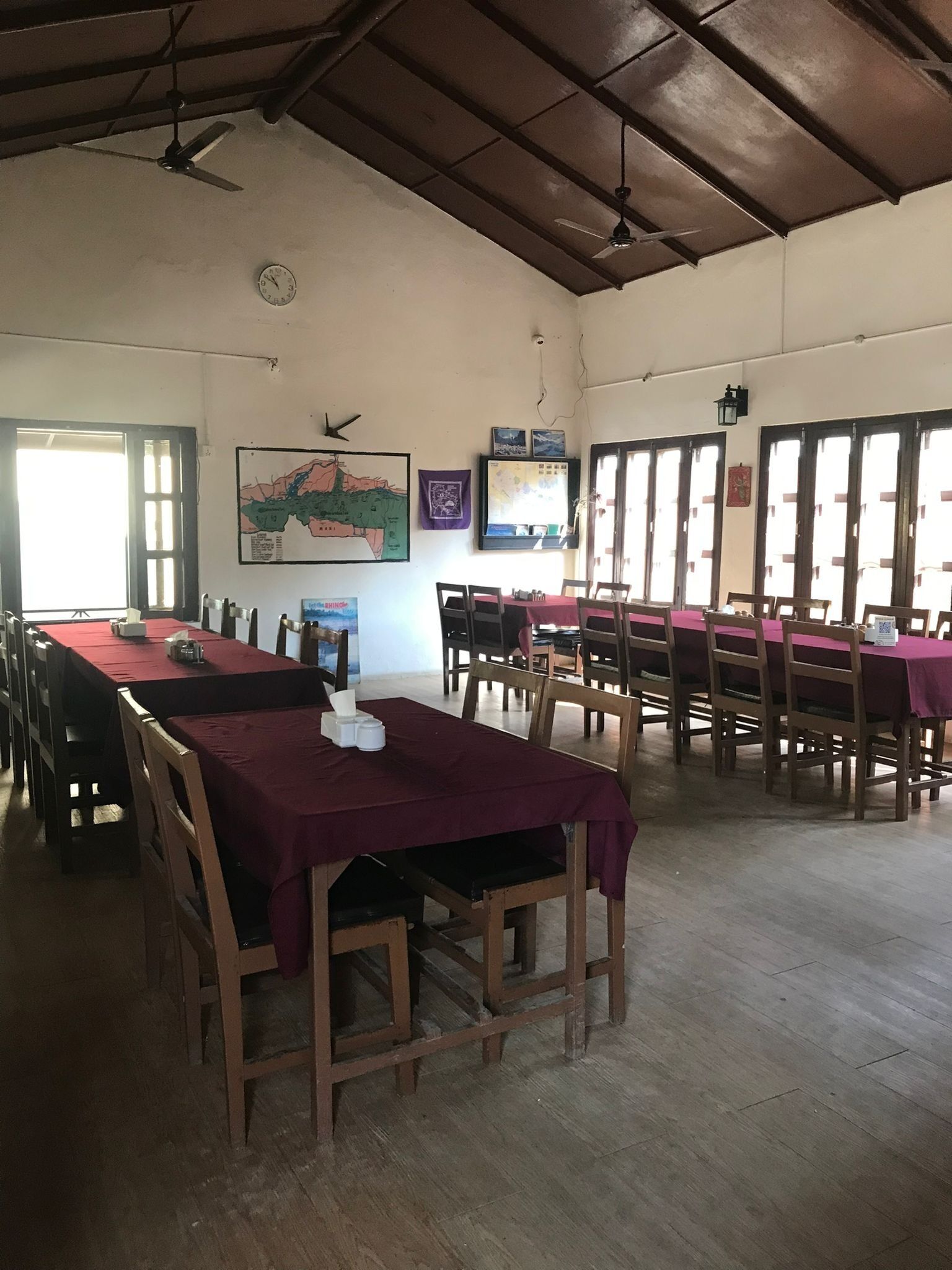 A spacious room with long tables and chairs, a clock on the wall, and a map.