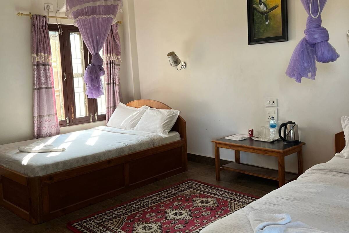 A bedroom with a bed, a nightstand, a ceiling fan, and a window with curtains.