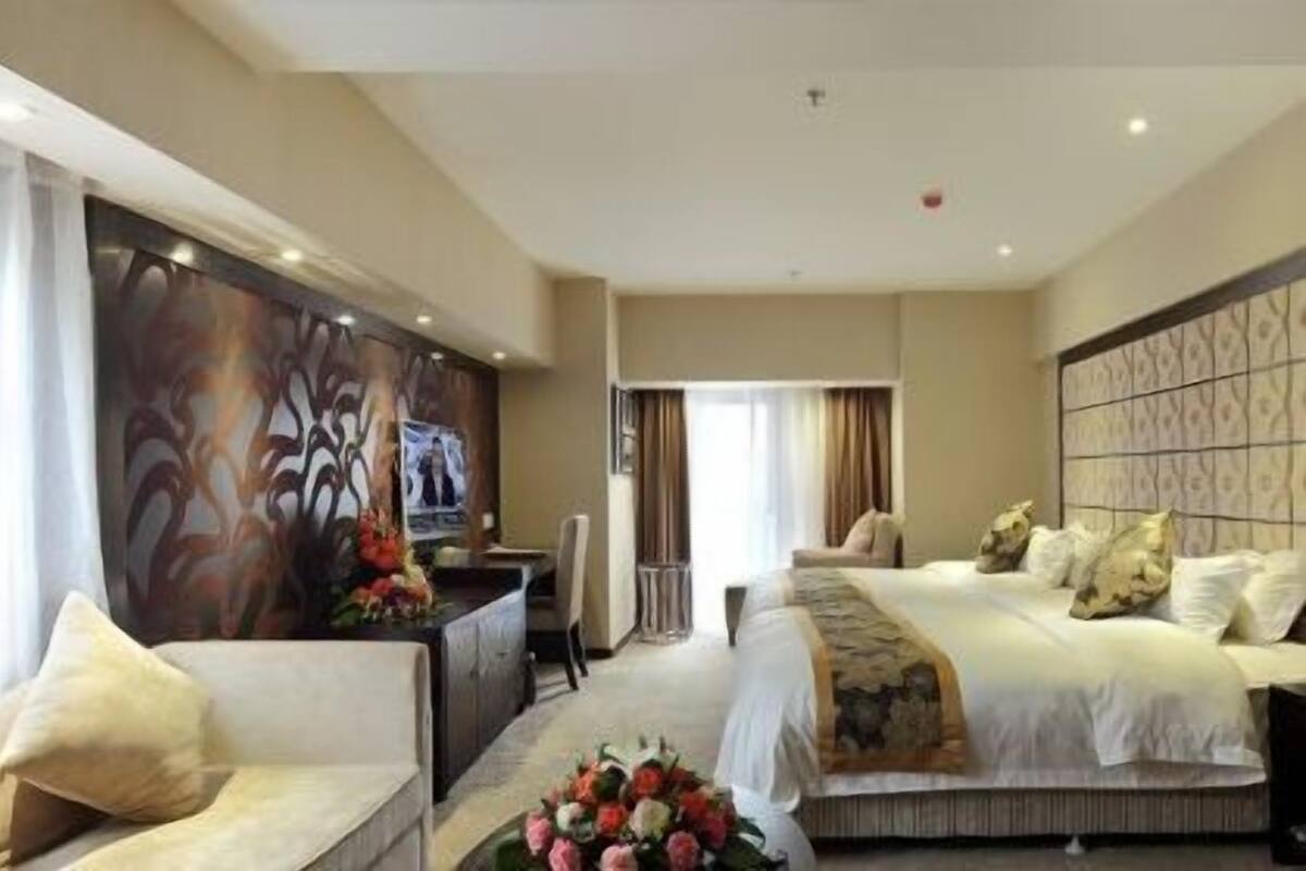 A hotel room with a bed, a desk, and a sofa.