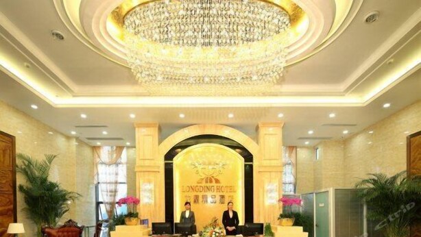 A hotel reception area with a chandelier, reception desk, and two receptionists. - Chongqing Longding Boutique Hotel (Chongqing)