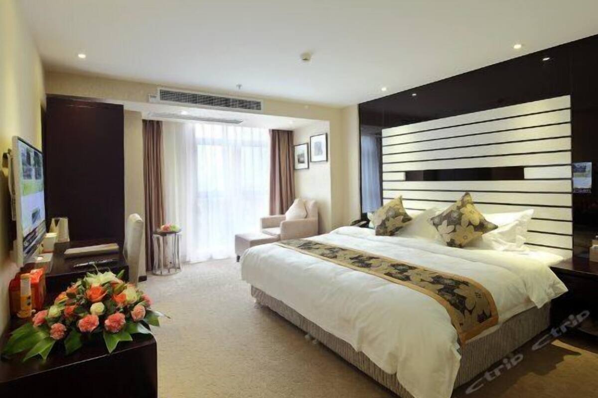 A hotel room with a large bed, a desk with a computer, a chair, and a TV.