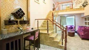 A modern interior with a kitchen area, a dining table with chairs, a staircase, and a seating area with a sofa. - Chongqing Longding Boutique Hotel (Chongqing)