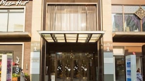A modern building with a glass entrance, a sign reading "Pizza Hut," and a person walking by. - Chongqing Longding Boutique Hotel (Chongqing)