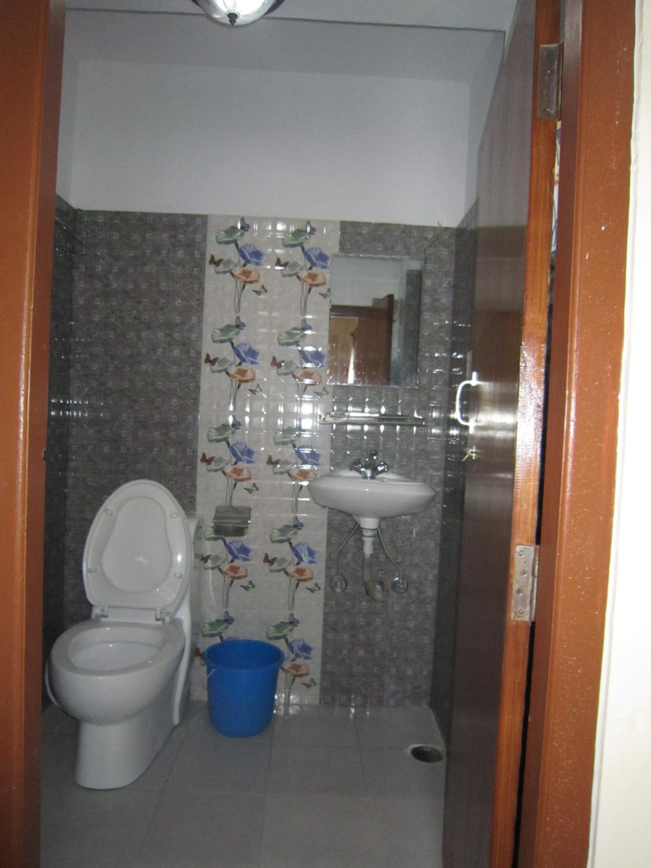 A small bathroom with a toilet, a sink, and a blue bucket.
