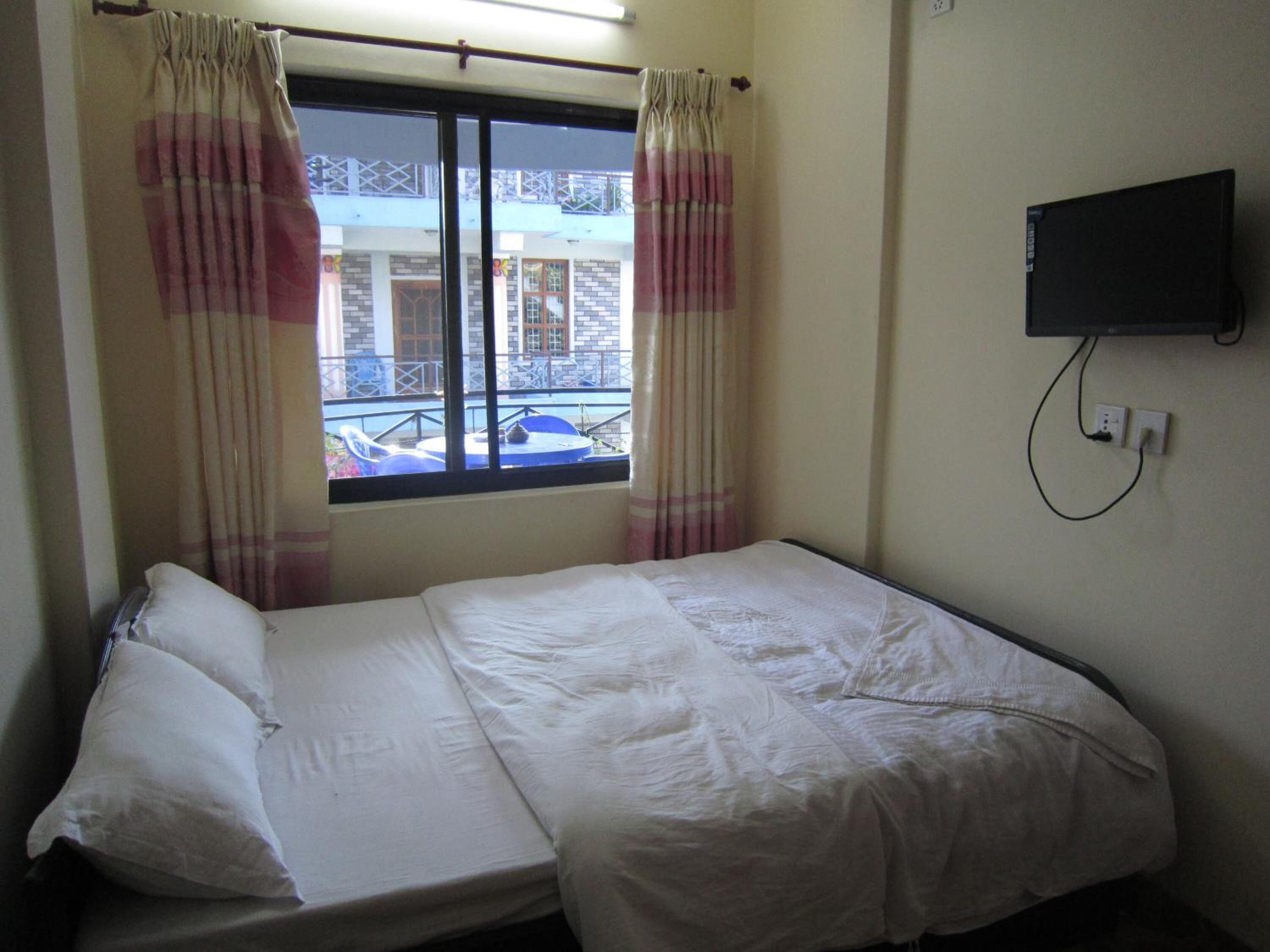Ein Einzelbett mit weißer Bettwäsche in einem Zimmer mit Fenster.