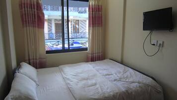 Ein Einzelbett mit weißer Bettwäsche in einem Zimmer mit Fenster.