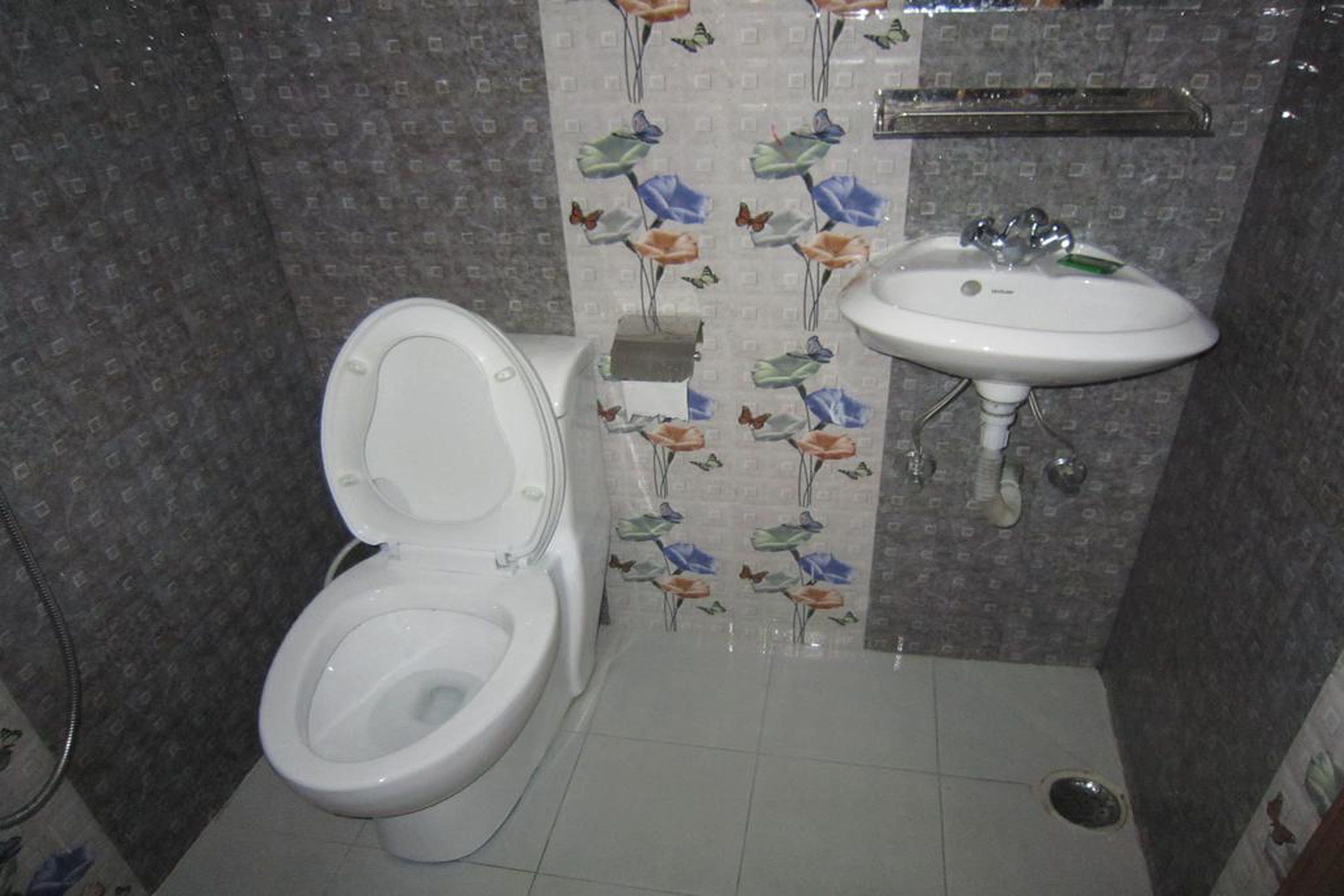 Et badeværelse med toilet, vask og bruser.