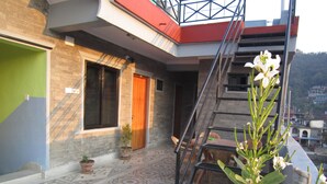 Una terraza en la azotea con suelo estampado, una planta en maceta y una escalera que lleva a un nivel superior.