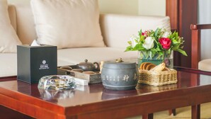 A wooden table with a tissue box, a teapot, a vase with flowers, and a basket of cookies. - Grand Szechuan Hotel Vientiane (Vientiane)