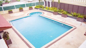 A rectangular swimming pool with a tiled deck, surrounded by planters with greenery. - Grand Szechuan Hotel Vientiane (Vientiane)