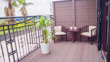 A balcony with two wooden chairs, a small table, and a potted plant.