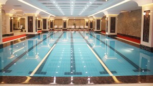 Una amplia piscina interior con suelo de baldosas e iluminación empotrada en el techo.
