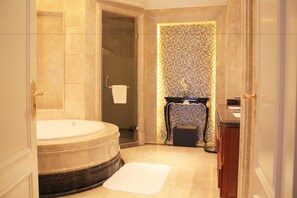 A spacious bathroom with a large bathtub, a shower area, and a sink with a decorative tile backsplash.
