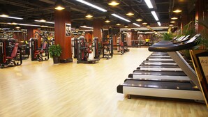 Un gimnasio con cintas de correr, máquinas de pesas y equipamiento de ejercicio.