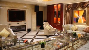 Un salón amplio con una televisión de pantalla plana grande, una chimenea y una zona de estar cómoda con sofás y sillones.