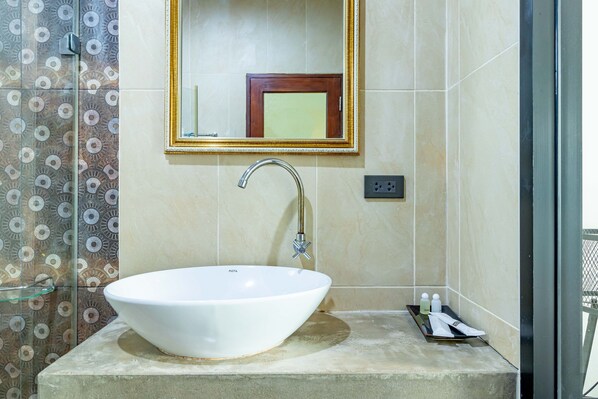 A bathroom with a white sink, a gold-framed mirror, and patterned tiles.