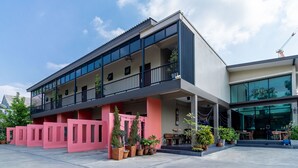 A modern building with a balcony, potted plants, and a glass entrance. - The Pool Resort (Bangkok)