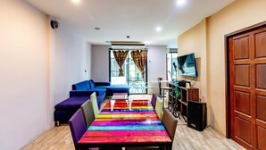 A modern living room with a long table, blue sofa, and a TV on the wall. - The Pool Resort (Bangkok)