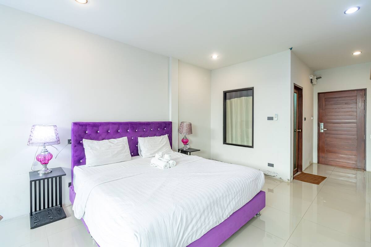 A modern bedroom with a large bed, two bedside tables, and a wooden door.