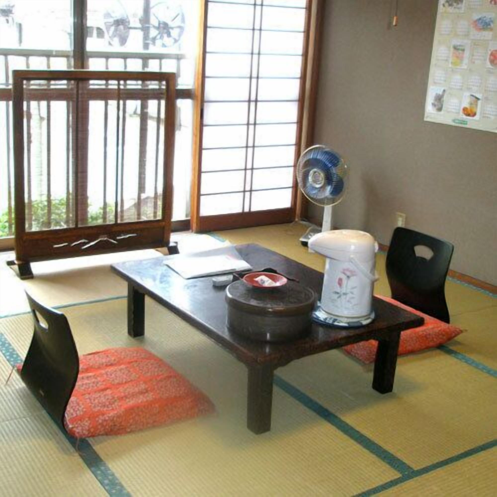 Une pièce de style japonais traditionnel, avec un sol recouvert de tatamis, une petite table basse, un éventail et un service à thé.