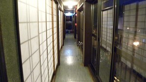 A narrow hallway with tiled walls and a reflective floor, leading to a door at the end. - Horieya Ryokan (Fukushima)