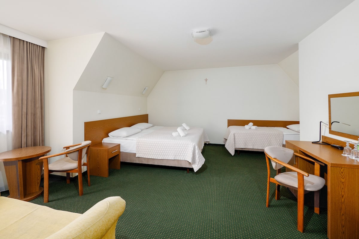 Habitación de hotel con dos camas, un escritorio, una silla y una mesita.