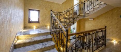 A marble staircase with wrought iron railings, leading to an upper floor.